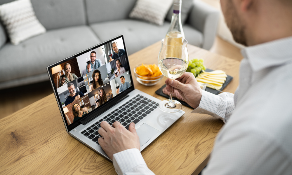 Man drinks wine and enjoys cheese board while on virtual meeting