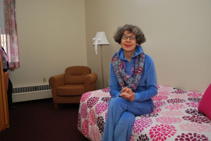elderly woman sits on bed